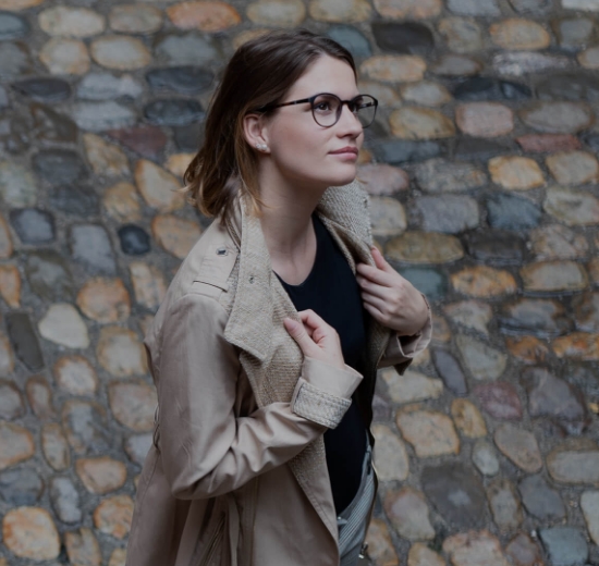 Frau mit Brille geht über Kopfsteinpflaster.